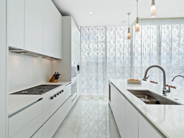 kitchen featuring white cabinets, sink, and decorative light fixtures