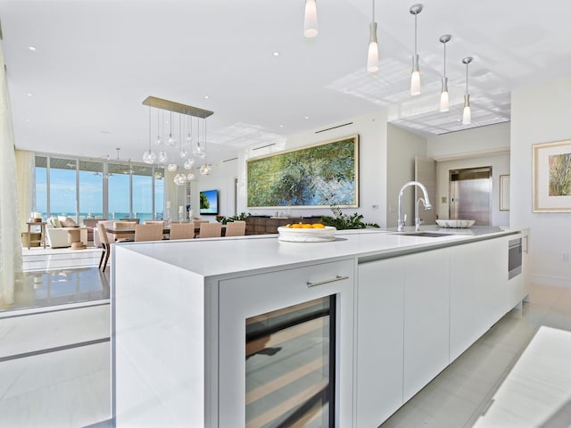 kitchen featuring white cabinetry, pendant lighting, sink, and beverage cooler