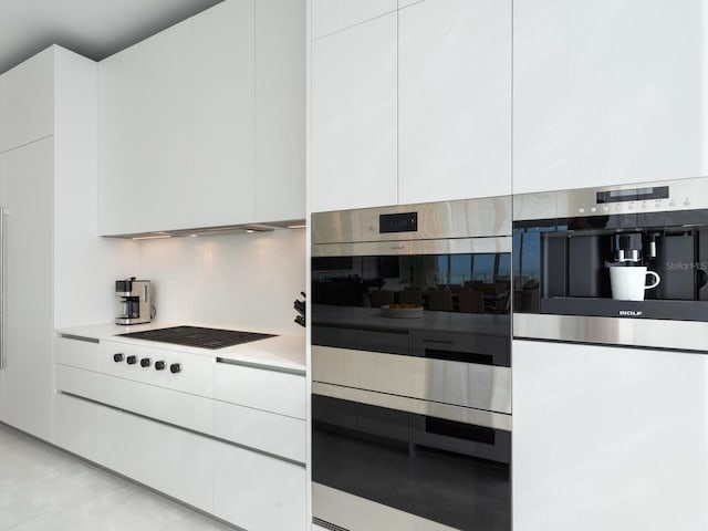 4651 Gulf Of Mexico Dr Unit 402, Longboat Key, FL 34228 - kitchen with modern cabinets, double wall oven, decorative backsplash, light countertops, and white cabinets