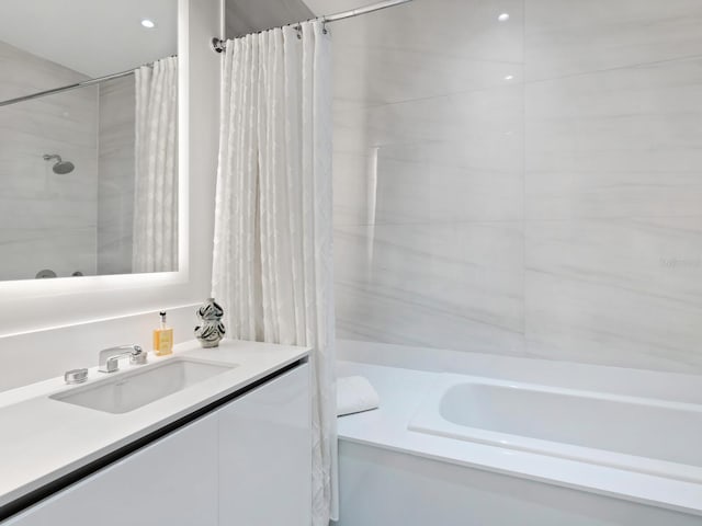 bathroom featuring vanity and shower / bathtub combination with curtain