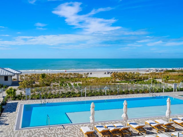 view of swimming pool featuring a view of the beach and a water view