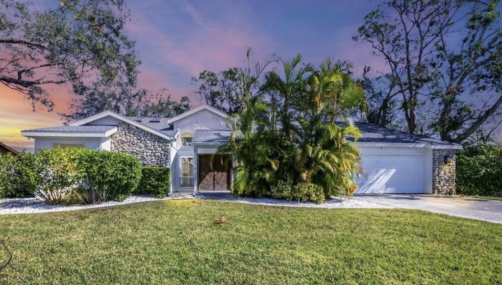 view of property hidden behind natural elements with a yard and a garage