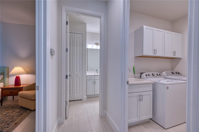 clothes washing area featuring washing machine and clothes dryer, cabinet space, and baseboards