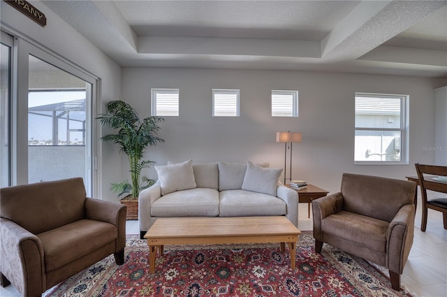 living room featuring a tray ceiling, plenty of natural light, and a textured ceiling