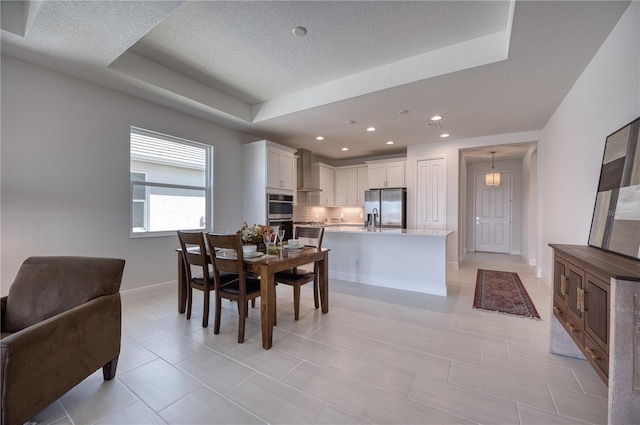 dining room featuring a raised ceiling, a textured ceiling, and baseboards