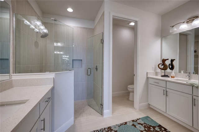 bathroom featuring a stall shower, toilet, a sink, tile patterned flooring, and two vanities