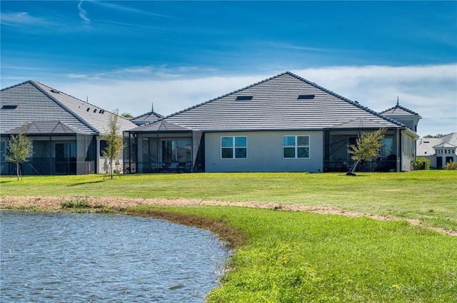 rear view of property featuring a lanai, stucco siding, a water view, and a yard