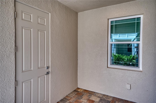 empty room with a textured wall and stone finish floor