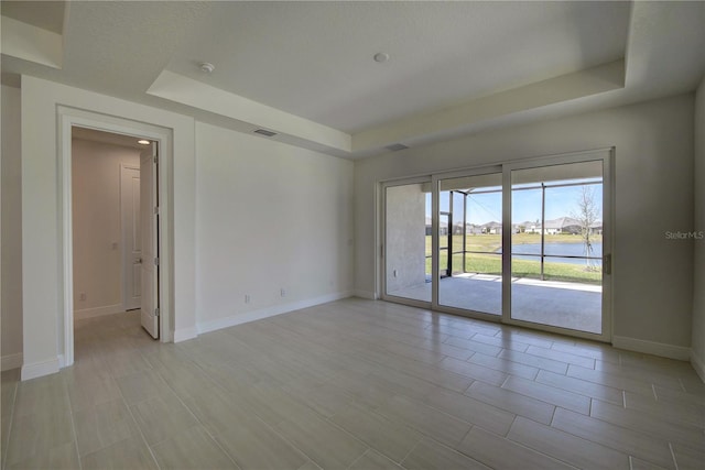 unfurnished room featuring a raised ceiling, visible vents, and baseboards