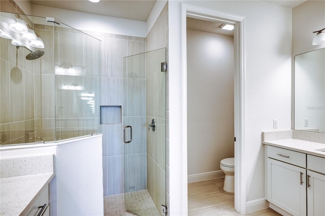 bathroom featuring toilet, a stall shower, vanity, and baseboards