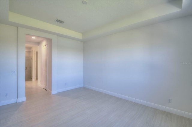 empty room featuring light wood-type flooring, visible vents, and baseboards