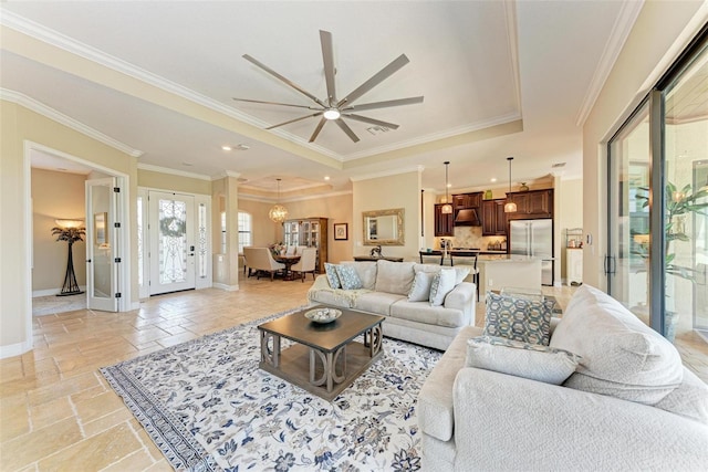 living room featuring ornamental molding, a tray ceiling, and ceiling fan with notable chandelier