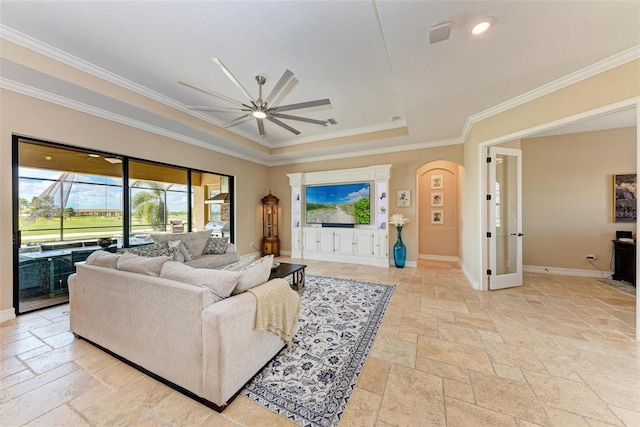 living room featuring ornamental molding, a tray ceiling, and ceiling fan