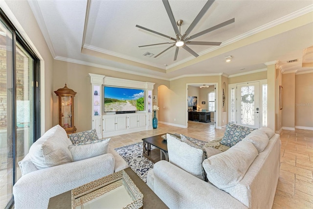 living room with crown molding, a tray ceiling, and ceiling fan