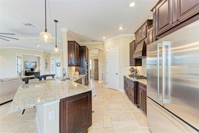 kitchen featuring a breakfast bar area, ornamental molding, sink, pendant lighting, and appliances with stainless steel finishes