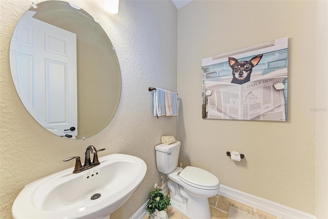 bathroom with toilet, sink, and tile patterned floors