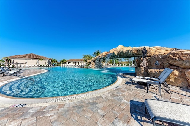 view of swimming pool with pool water feature and a patio area