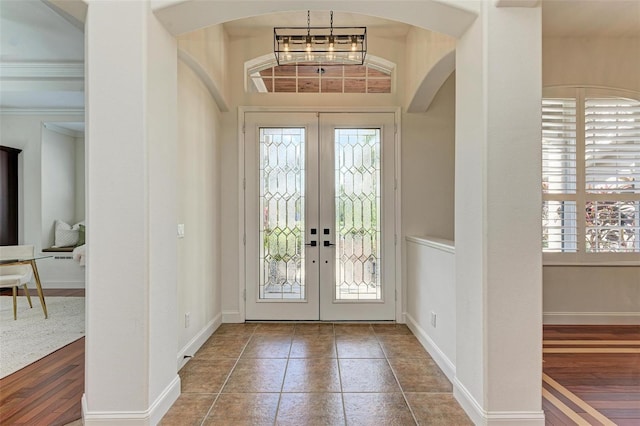 foyer entrance with french doors, an inviting chandelier, a healthy amount of sunlight, and hardwood / wood-style flooring