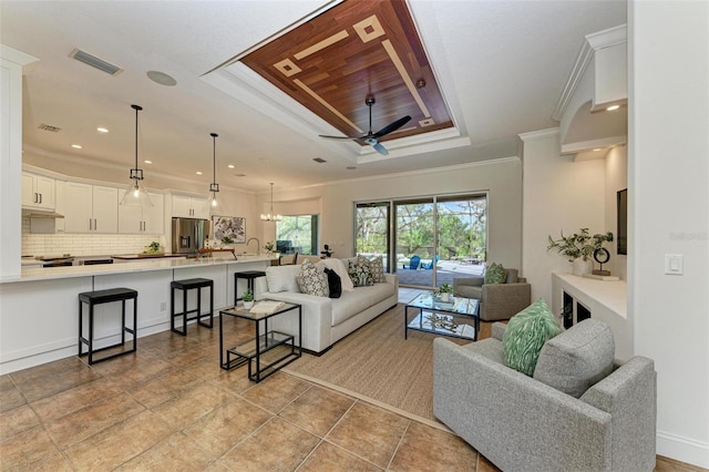 tiled living room featuring a raised ceiling, ceiling fan, ornamental molding, and sink