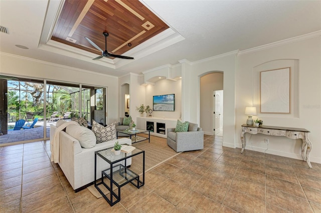 living room featuring a tray ceiling, ceiling fan, and ornamental molding