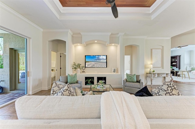 living room featuring wood-type flooring, ceiling fan, and ornamental molding