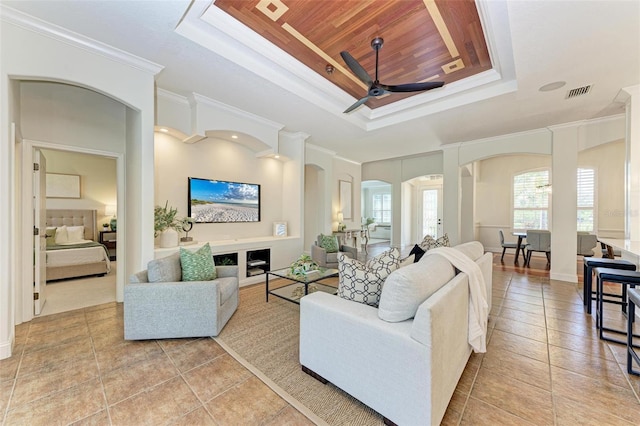 tiled living room with a tray ceiling, ceiling fan, and crown molding