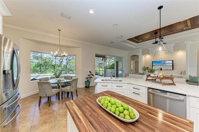 kitchen featuring pendant lighting, an inviting chandelier, white cabinets, appliances with stainless steel finishes, and light stone counters