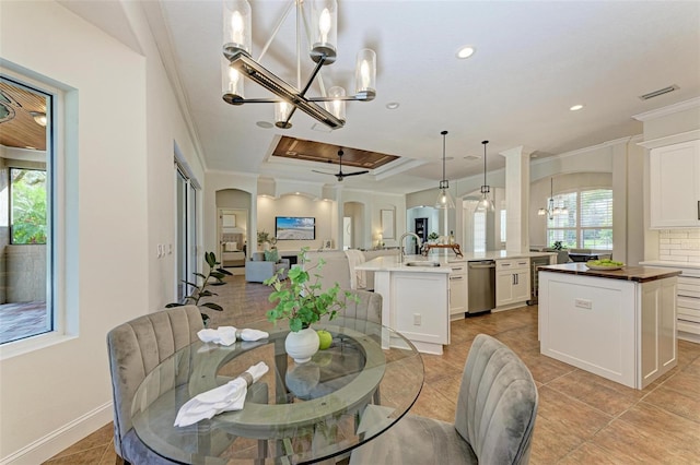 tiled dining area featuring a raised ceiling, ceiling fan, sink, and ornamental molding