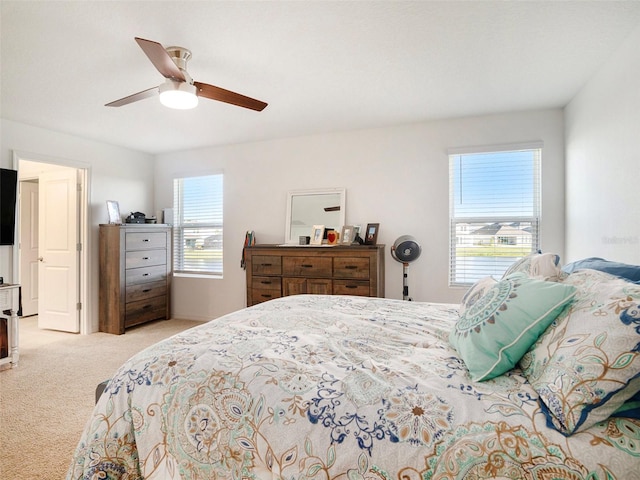 carpeted bedroom featuring multiple windows and ceiling fan