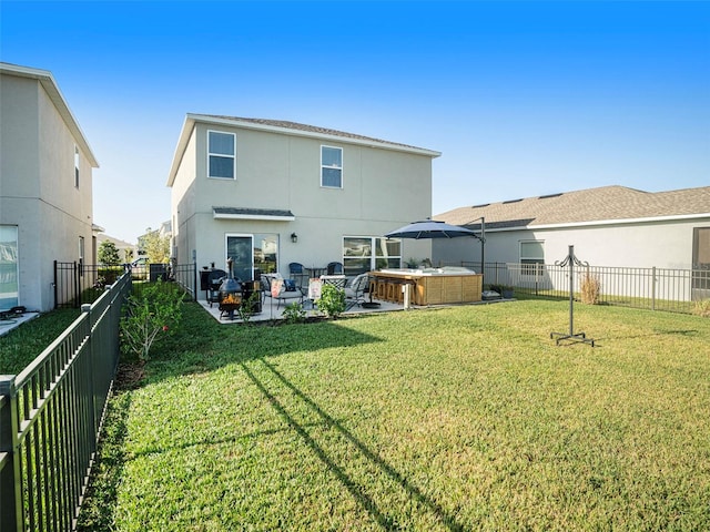 rear view of house with a yard, a hot tub, and a patio area