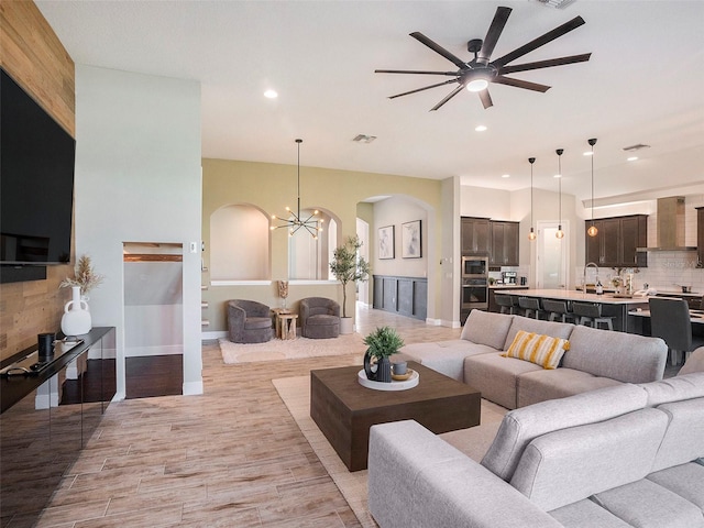 living room featuring light hardwood / wood-style floors and ceiling fan with notable chandelier