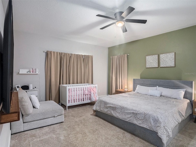 carpeted bedroom featuring ceiling fan and a textured ceiling