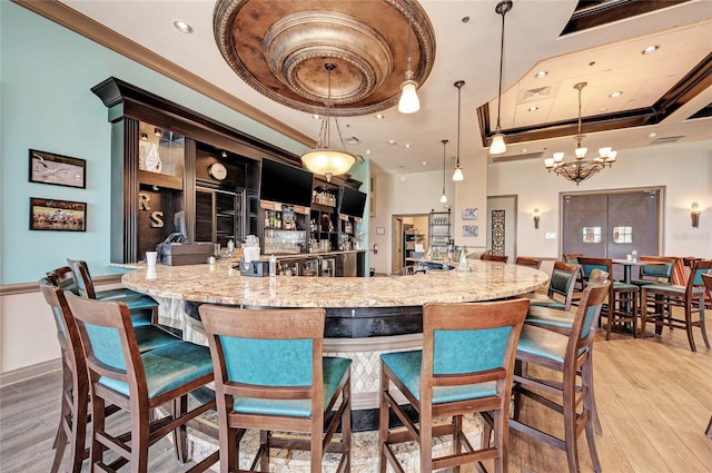 bar featuring light hardwood / wood-style flooring, a tray ceiling, and pendant lighting