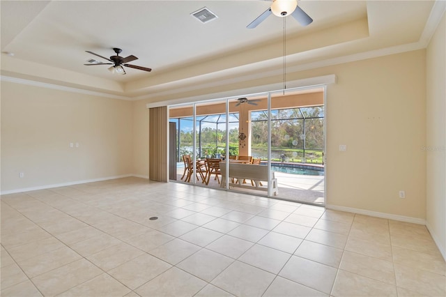 tiled empty room featuring a raised ceiling, ceiling fan, and ornamental molding