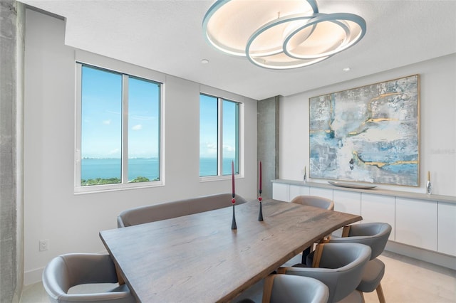 dining room with a healthy amount of sunlight, a water view, and a textured ceiling