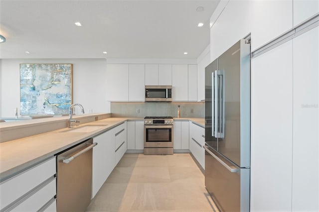 kitchen with tasteful backsplash, appliances with stainless steel finishes, sink, and white cabinets