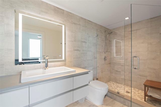 bathroom featuring a shower with door, tile patterned flooring, vanity, toilet, and tile walls