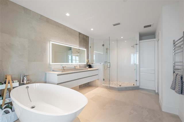 bathroom featuring vanity, plus walk in shower, and tile walls