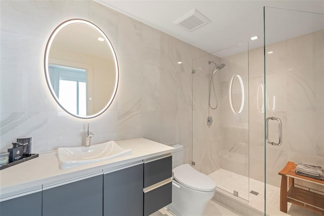 bathroom featuring a shower with shower door, vanity, toilet, and tile walls