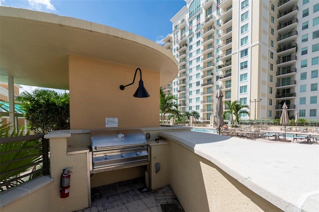 view of patio / terrace featuring a balcony, area for grilling, and a community pool