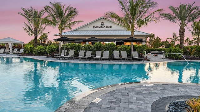 pool at dusk featuring a gazebo and a patio