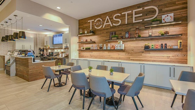 bar featuring decorative light fixtures, wooden walls, and tasteful backsplash