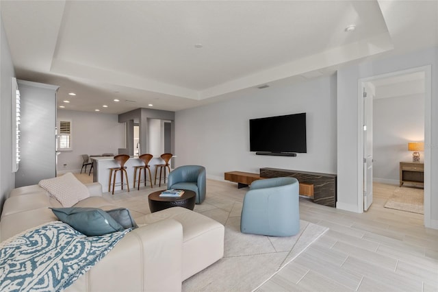 living room with light hardwood / wood-style floors and a raised ceiling