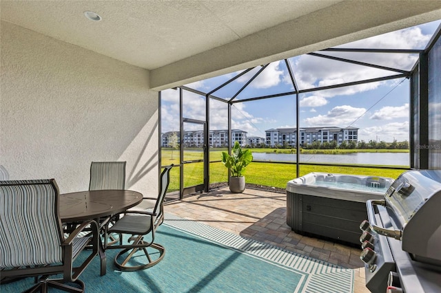 sunroom featuring a hot tub and a water view