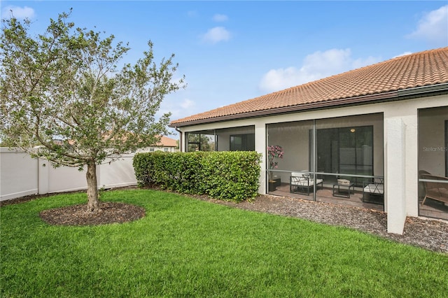 back of property with a lawn and a sunroom