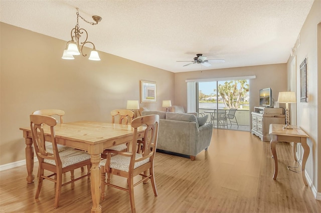 dining space with light hardwood / wood-style flooring, a textured ceiling, and ceiling fan with notable chandelier