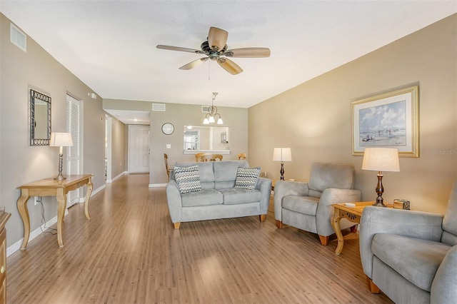 living room with light hardwood / wood-style flooring and ceiling fan with notable chandelier