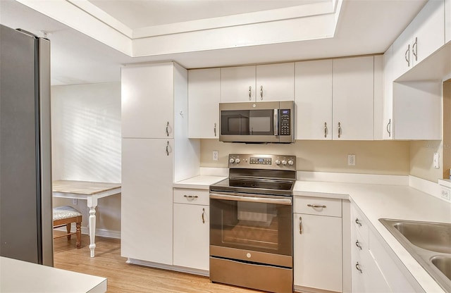 kitchen featuring white cabinetry, appliances with stainless steel finishes, light hardwood / wood-style flooring, and sink