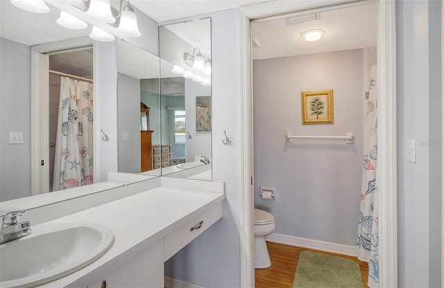 bathroom with toilet, a textured ceiling, hardwood / wood-style flooring, and vanity