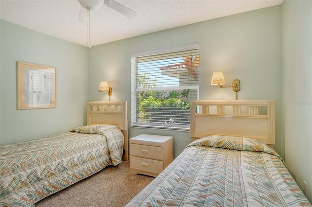 bedroom with a textured ceiling, light colored carpet, and ceiling fan